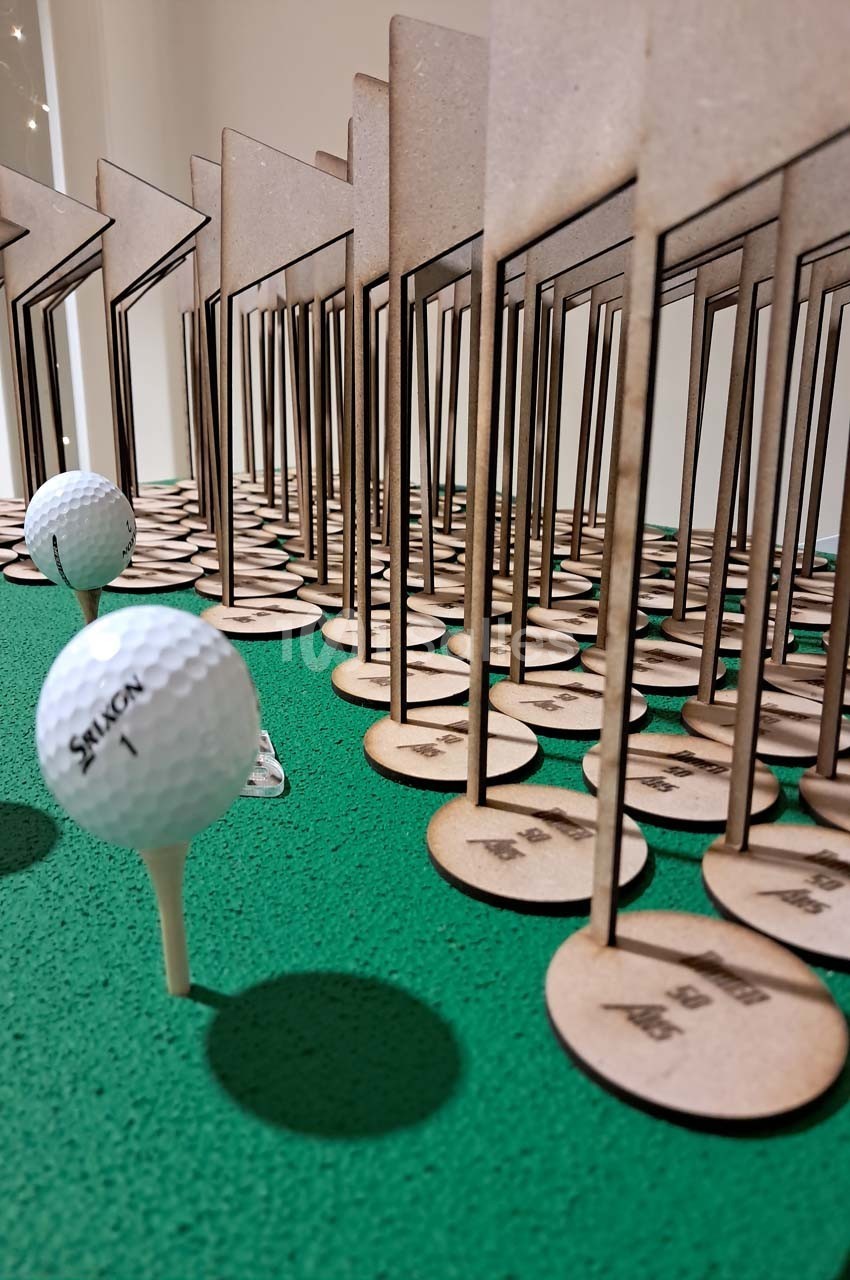 Des balles de golf sur des tees devant des panneaux en bois alignés sur une surface verte.