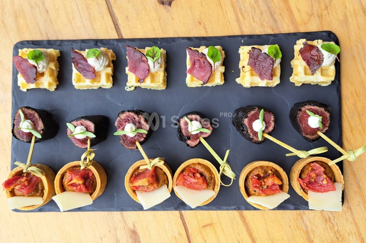 Plateau de bouchées apéritives variées comprenant mini-gaufres, champignons farcis et tartelettes garnies.