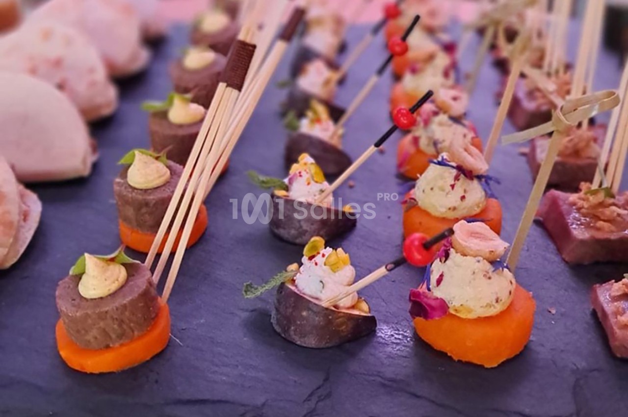 Plateau d'amuse-bouches variés disposés sur une ardoise, avec brochettes et garnitures colorées.