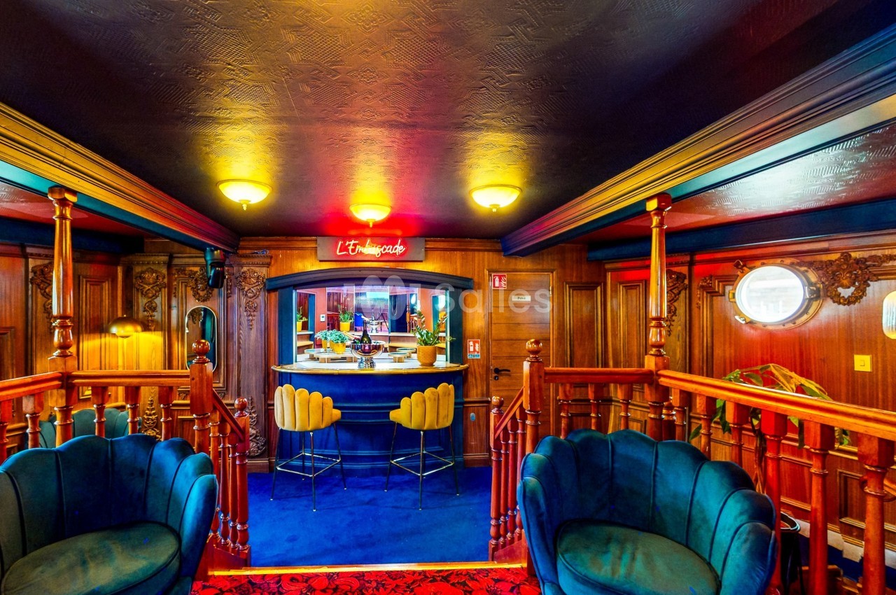 Intérieur d'un bar au style rétro avec fauteuils en velours, comptoir central et éclairage chaleureux.