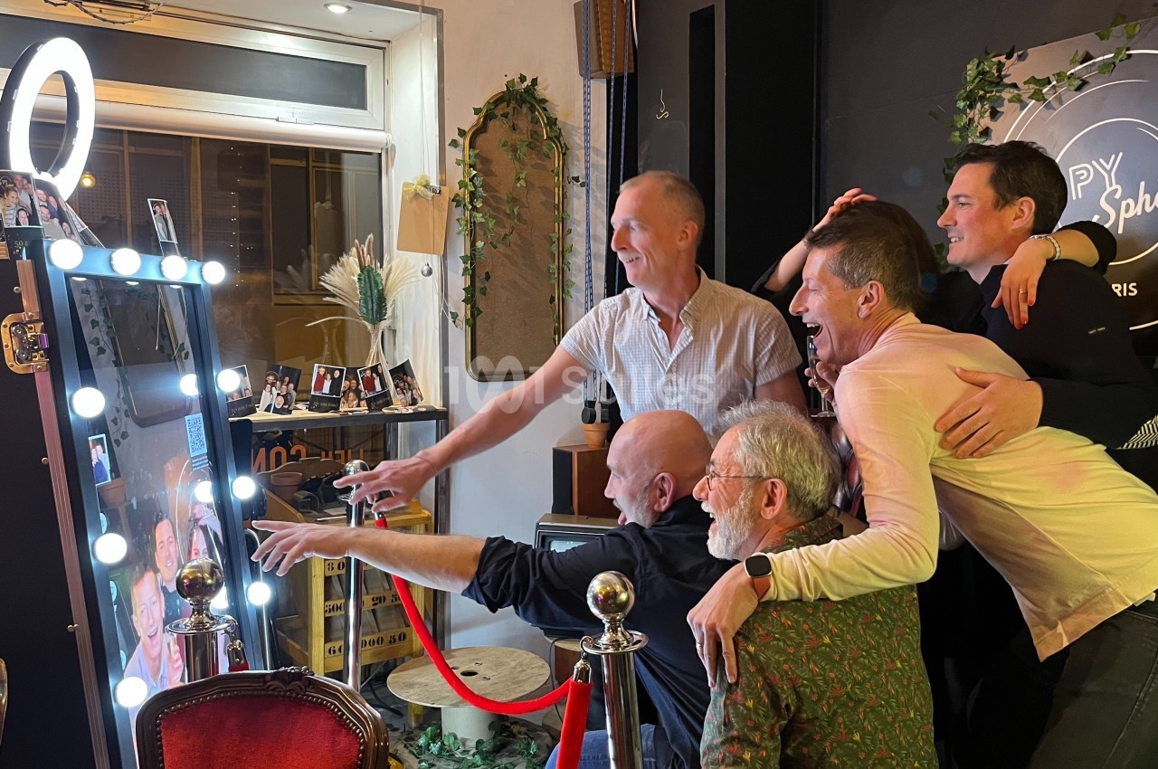 Un groupe de personnes souriantes pose devant un miroir interactif lumineux dans un cadre festif.