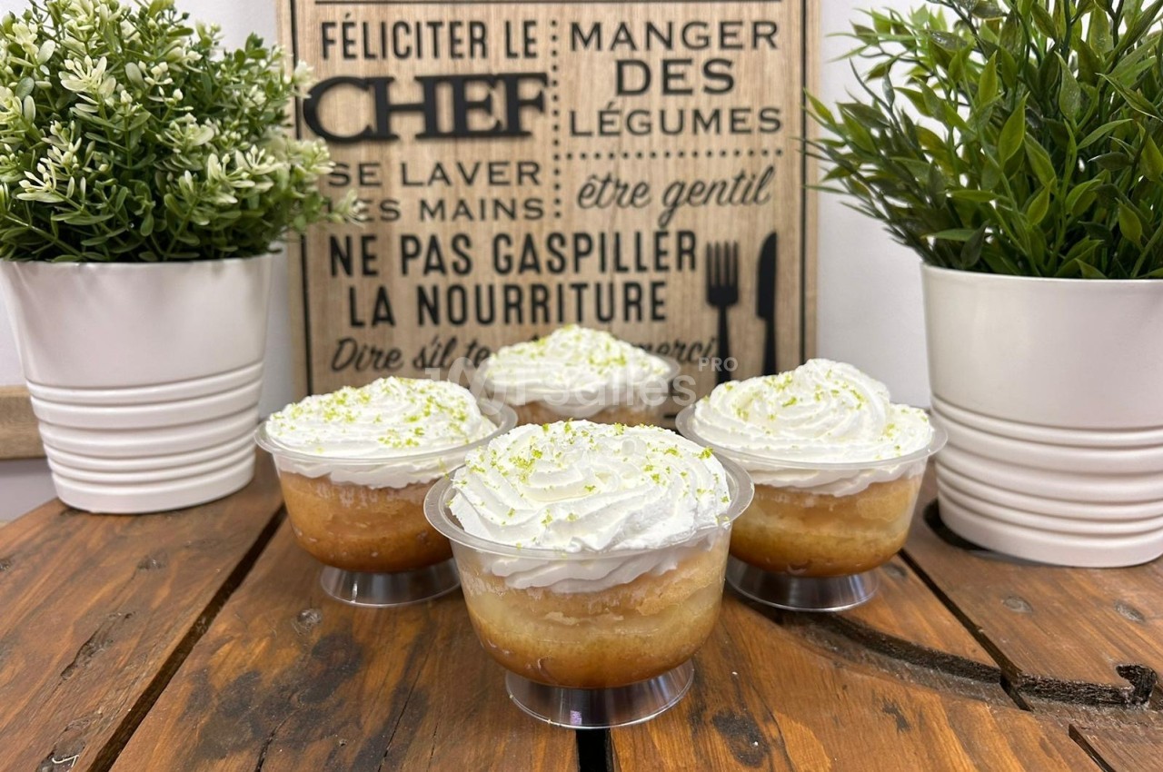 Quatre verrines de dessert à base de pommes et chantilly, décorées de zestes, posées sur une table en bois.