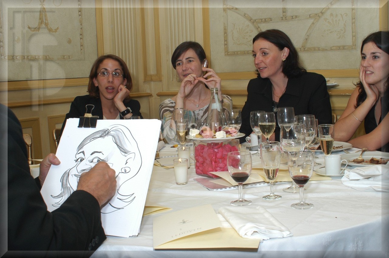 Un caricaturiste dessine une femme assise à une table lors d'un dîner, entourée de convives amusées.