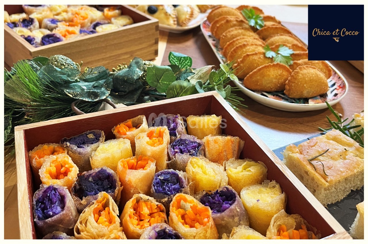 Plateaux de bouchées colorées aux légumes, feuilletés dorés et focaccia, disposés sur une table décorée.