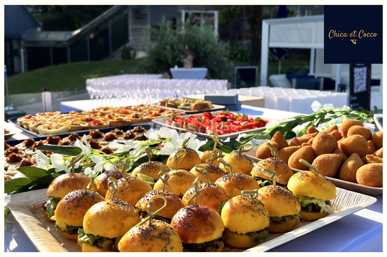 Plateau de mini-burgers, bouchées salées et verrines disposés sur une table pour un buffet en extérieur.