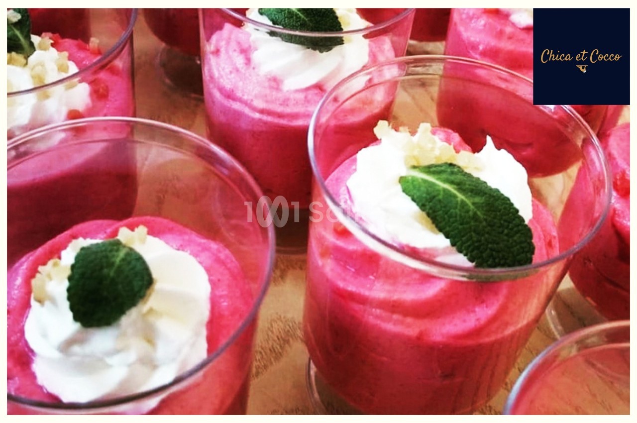 Verrines de mousse rose garnies de crème fouettée, feuilles de menthe et éclats décoratifs.