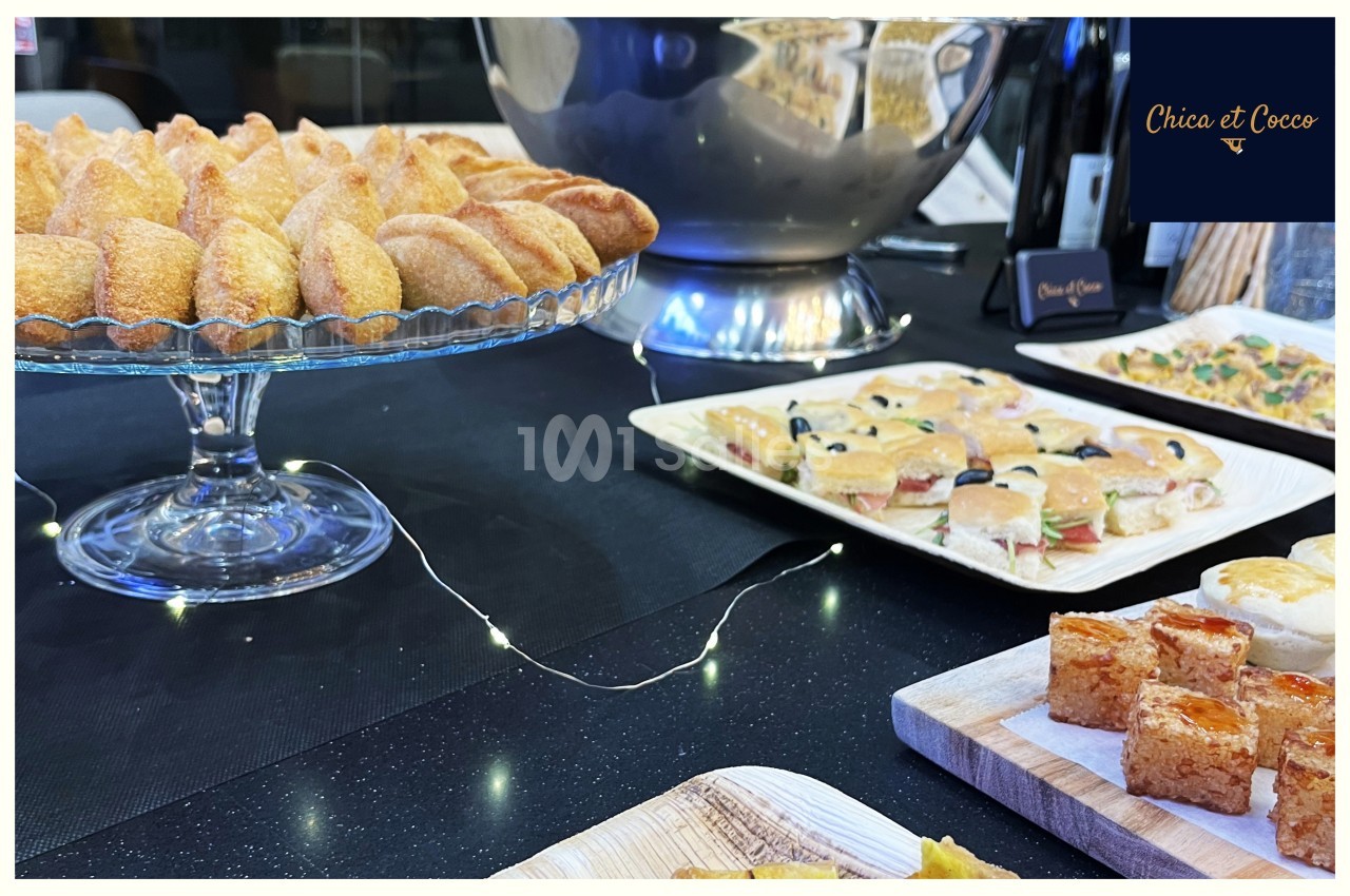 Plateau de pâtisseries et amuse-bouches variés disposés sur une table noire avec une décoration lumineuse.