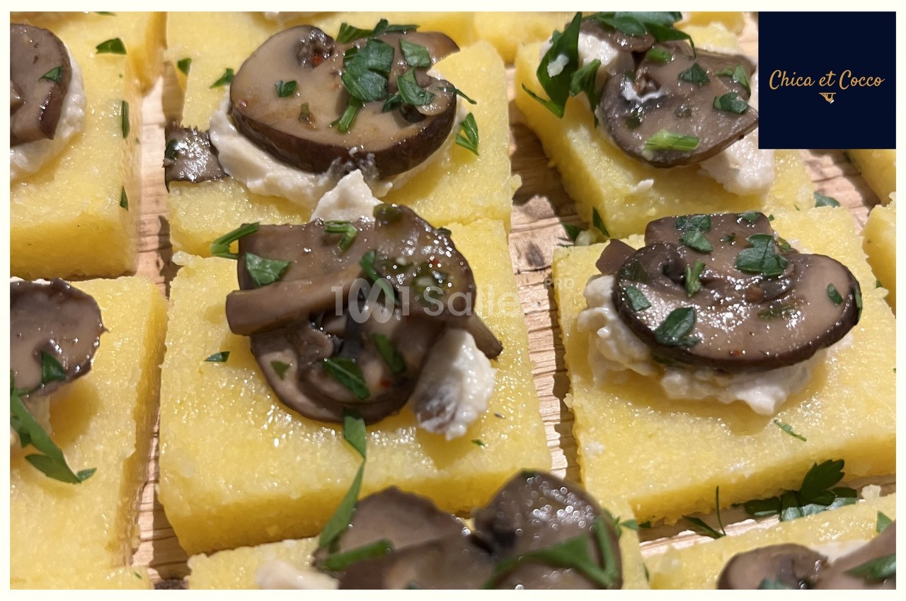 Carrés de polenta garnis de champignons sautés, fromage frais et persil haché, disposés sur une planche en bois.