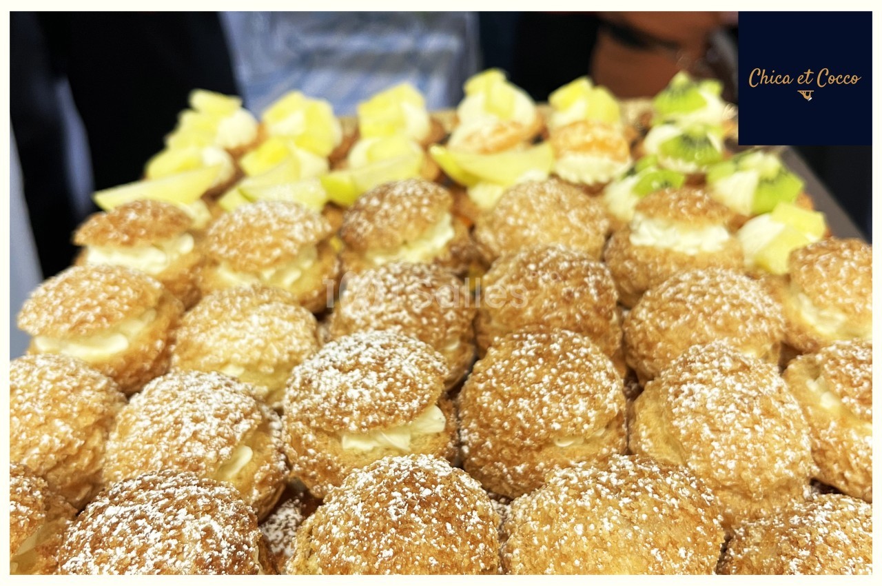 Plateau de choux à la crème saupoudrés de sucre glace, accompagnés de morceaux de citron en décoration.