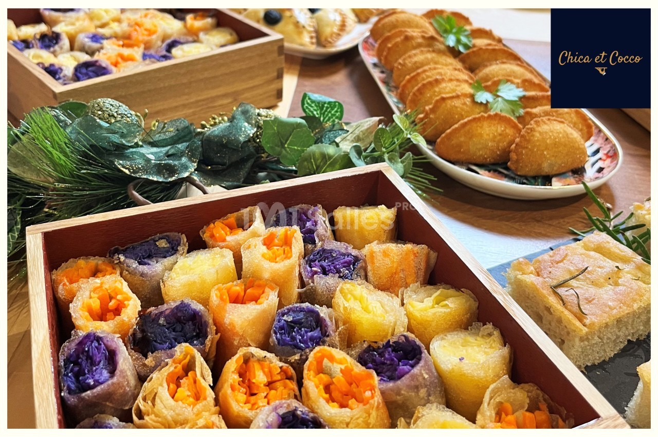 Plateaux de rouleaux de légumes colorés, feuilletés dorés et focaccia, présentés sur une table décorée.