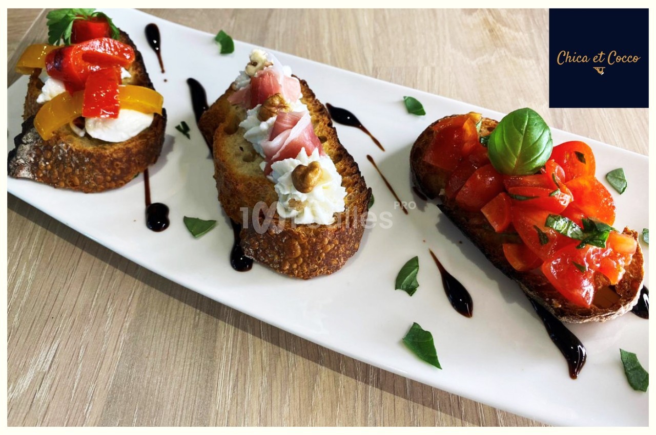 Assortiment de bruschettas garnies de légumes, fromage, jambon et noix, présenté sur une assiette blanche.