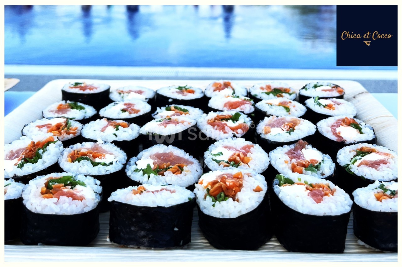 Assortiment de makis au saumon, fromage frais et légumes, disposés sur un plateau en bois.