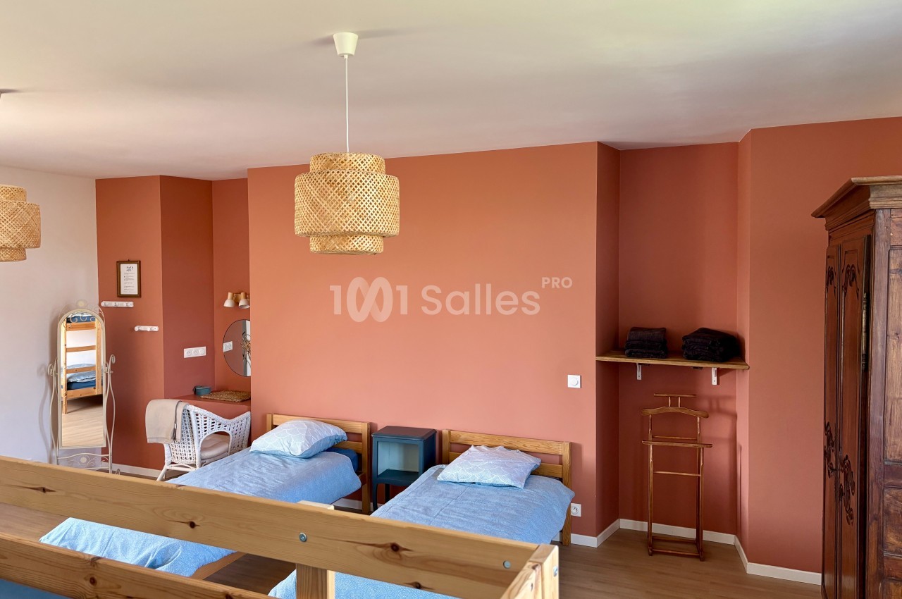 Chambre lumineuse avec murs orange, deux lits simples, mobilier en bois et éléments de décoration en rotin.