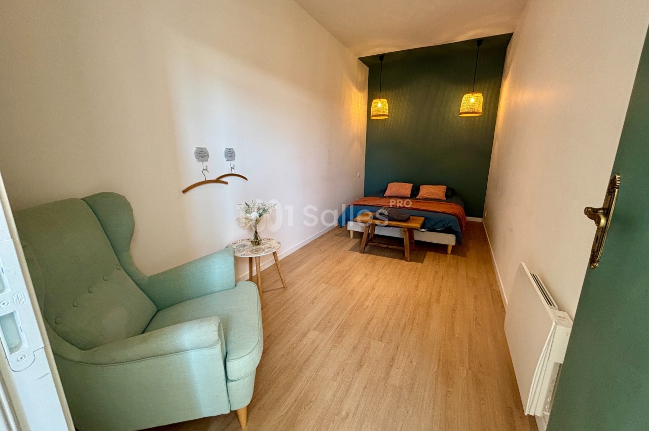 Chambre lumineuse avec un lit double, un fauteuil vert, des lampes suspendues et un mur d'accent vert.