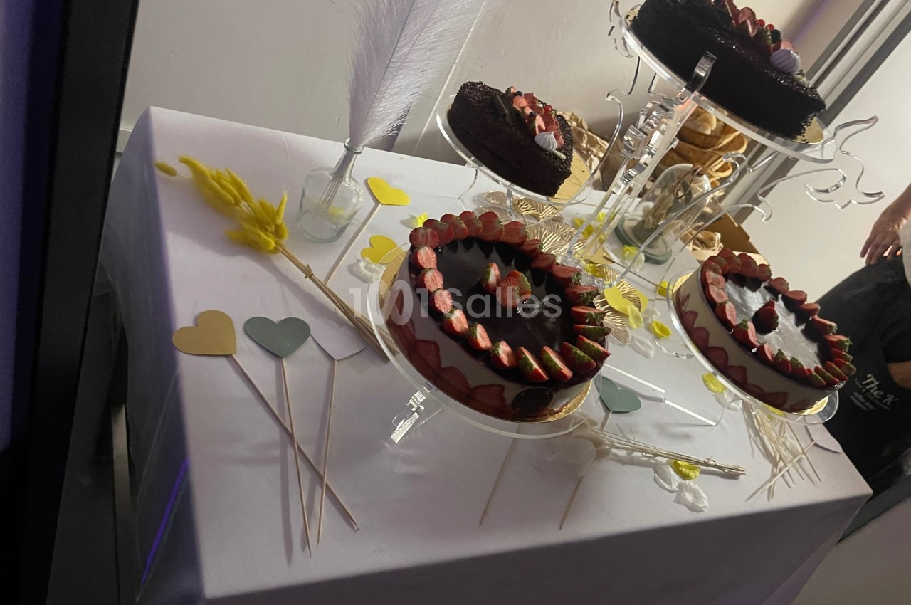 Gâteaux au chocolat décorés de fraises sur une table blanche, entourés de décorations en forme de cœurs colorés.