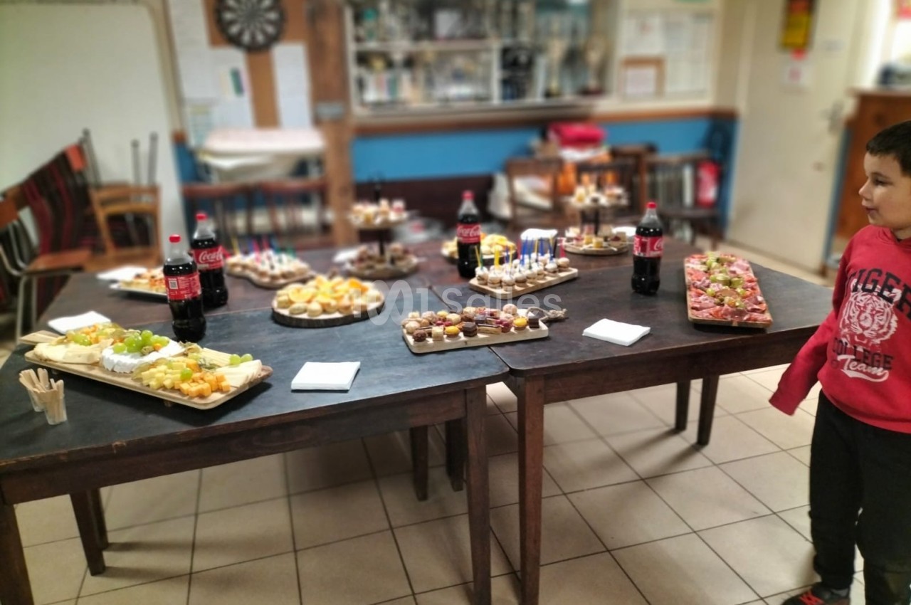 Buffet composé de plateaux de nourriture variée et de bouteilles de soda, disposé sur des tables dans une salle.