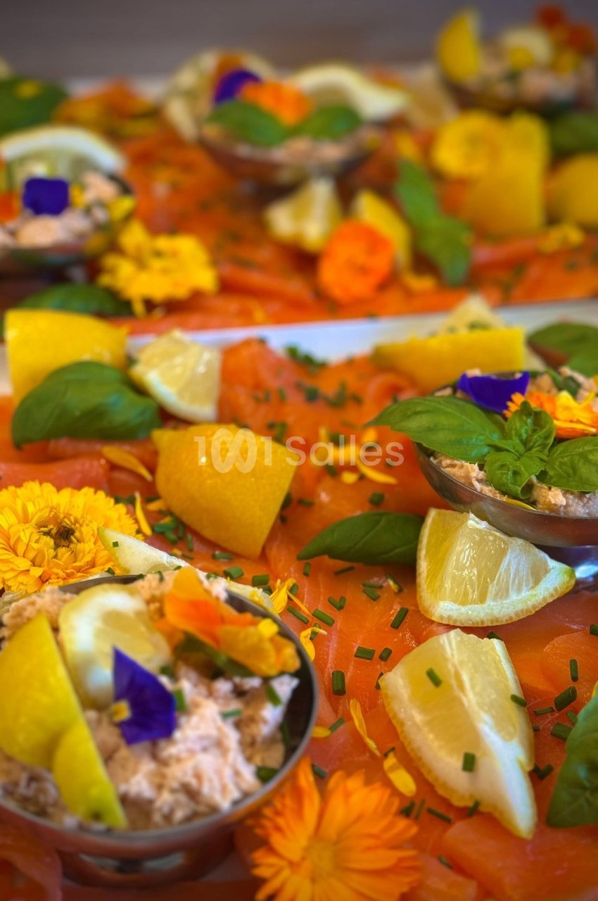 Plateau de saumon fumé garni de rondelles de citron, fleurs comestibles et herbes fraîches.