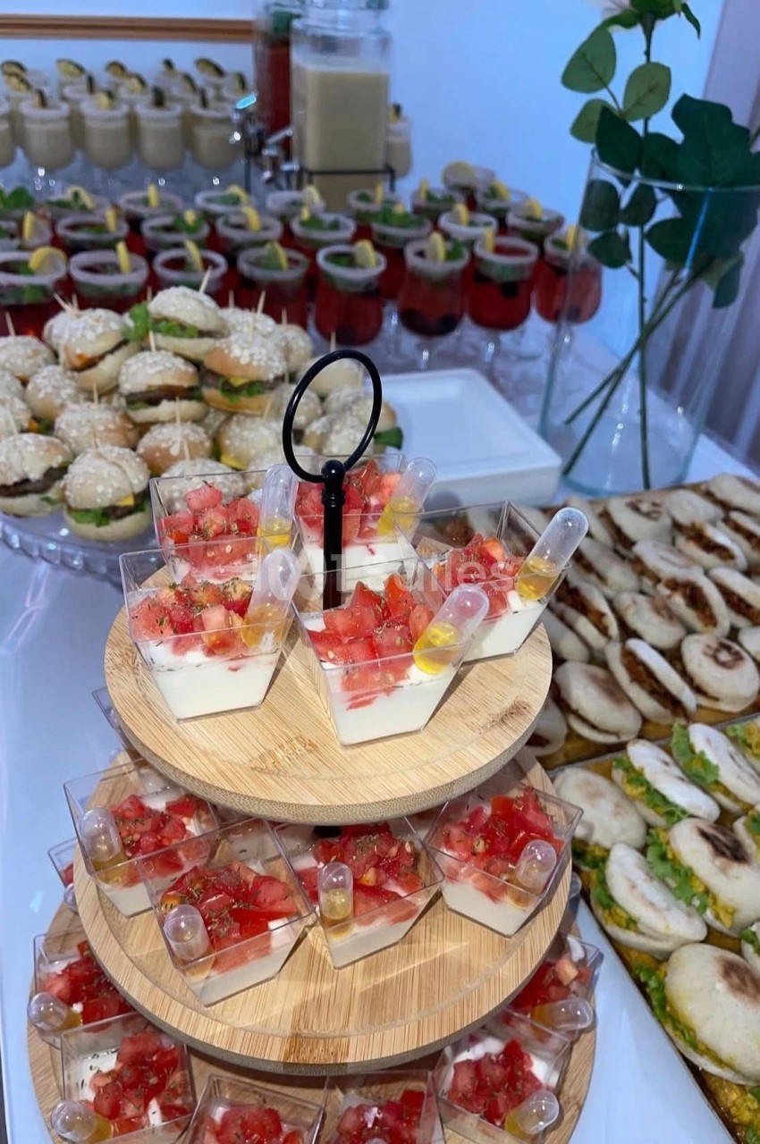 Buffet avec verrines de dessert, mini-sandwiches, roulés salés et desserts en arrière-plan.