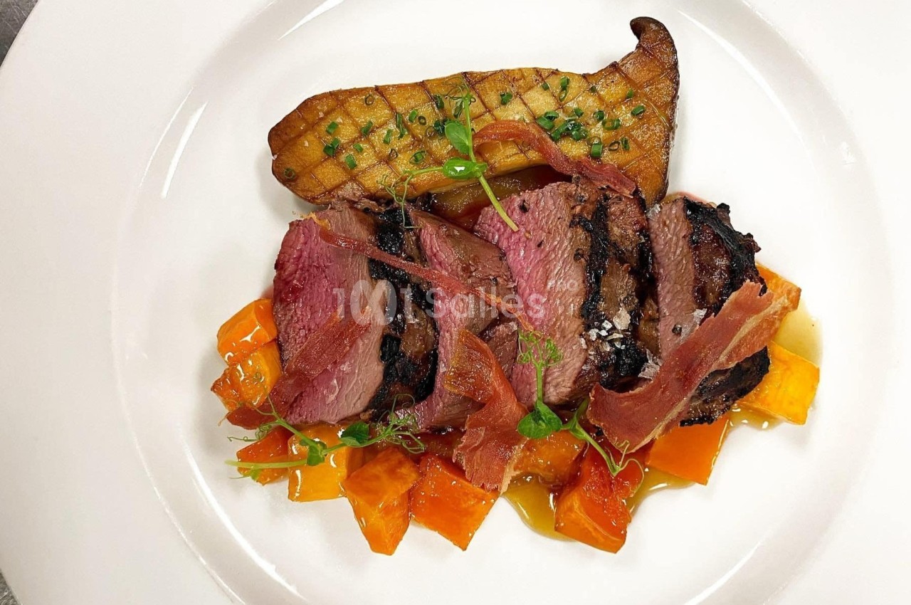 Assiette gastronomique avec magret de canard, patate douce, chips de jambon et garniture de poireau grillé.