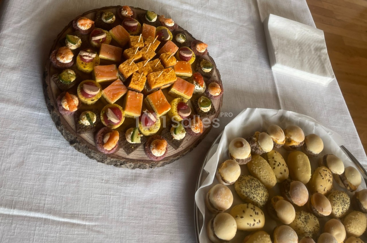 Plateaux de mignardises salées et pains variés disposés sur une table recouverte d'une nappe blanche.