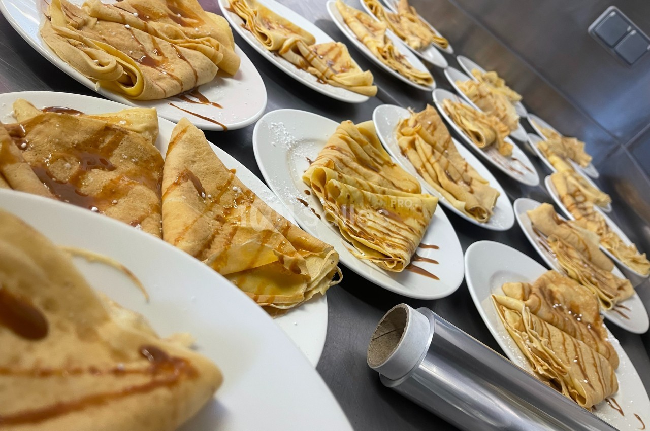 Assiettes de crêpes pliées, garnies de caramel, disposées sur un plan de travail en cuisine.