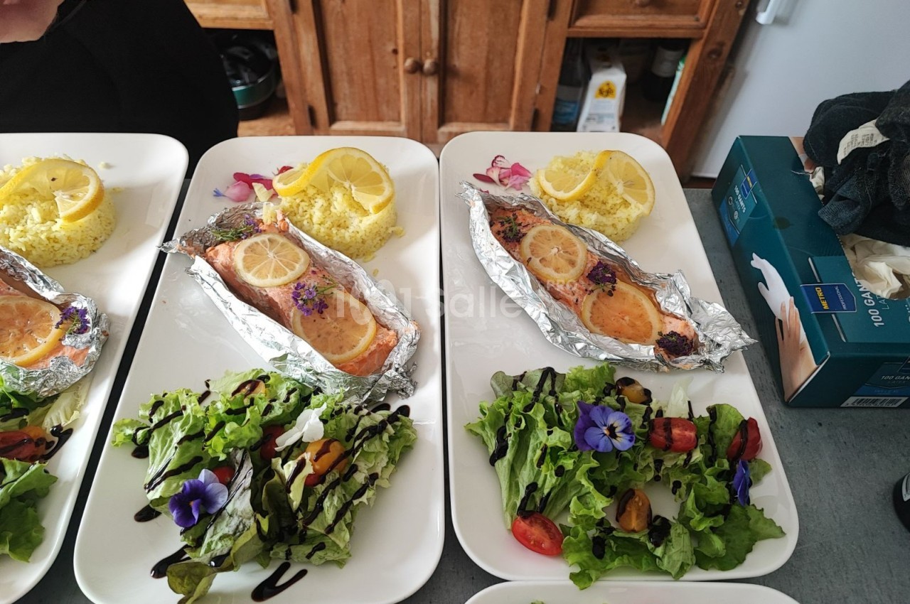 Assiettes composées de saumon en papillote avec rondelles de citron, salade garnie et riz accompagné de citron.