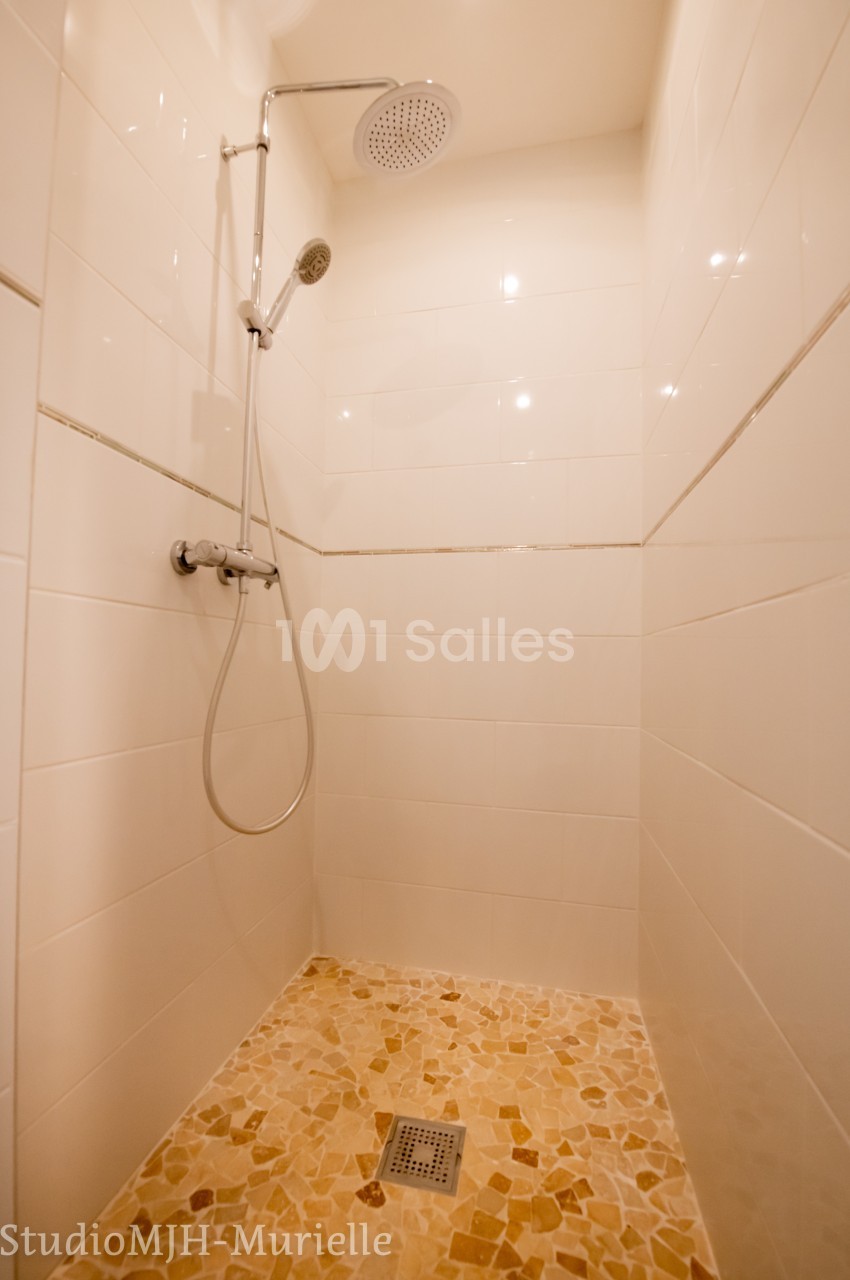 Douche à l'italienne avec carrelage au sol en pierre naturelle et murs en faïence blanche.