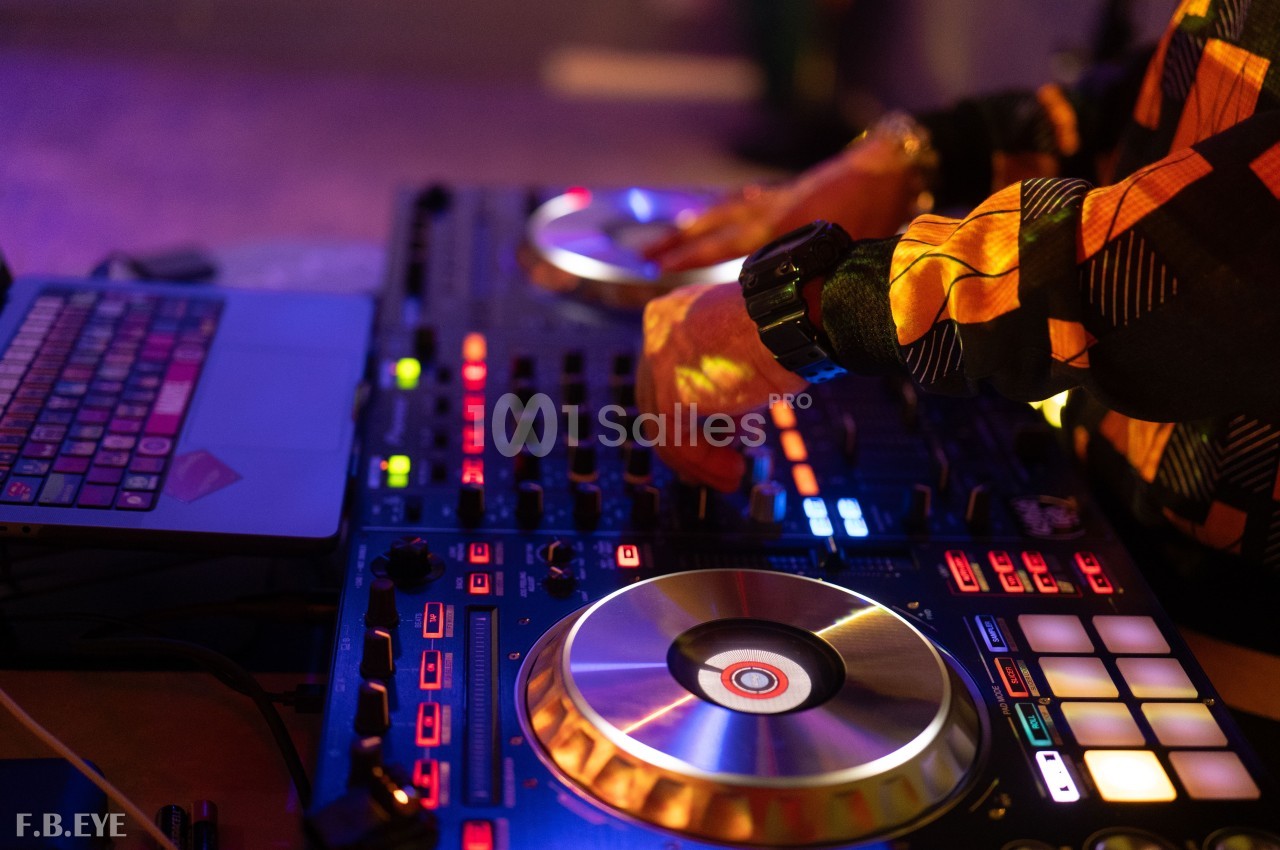 Un DJ mixant de la musique sur une table de mixage éclairée par des lumières colorées.