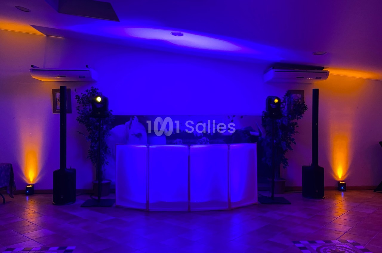 Salle de réception avec éclairage d'ambiance violet et orange, table centrale éclairée et équipements audio visibles.