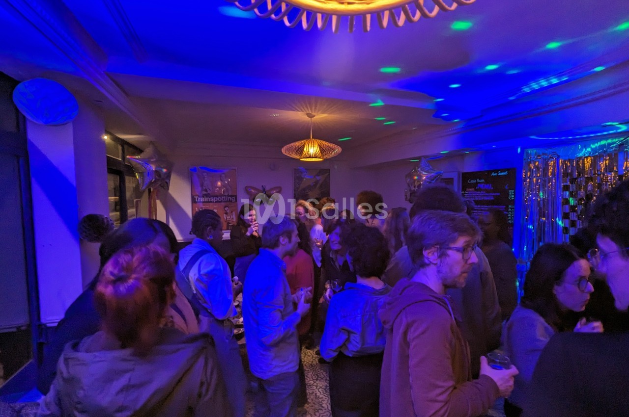 Groupe de personnes discutant dans une salle éclairée par des lumières colorées lors d'un événement festif.