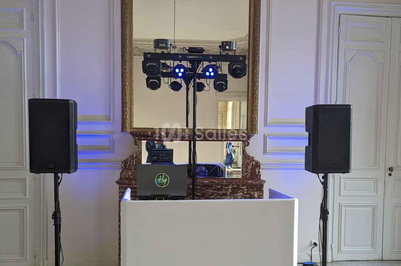 Installation de matériel de sonorisation et d'éclairage devant une cheminée avec miroir dans une pièce élégante.