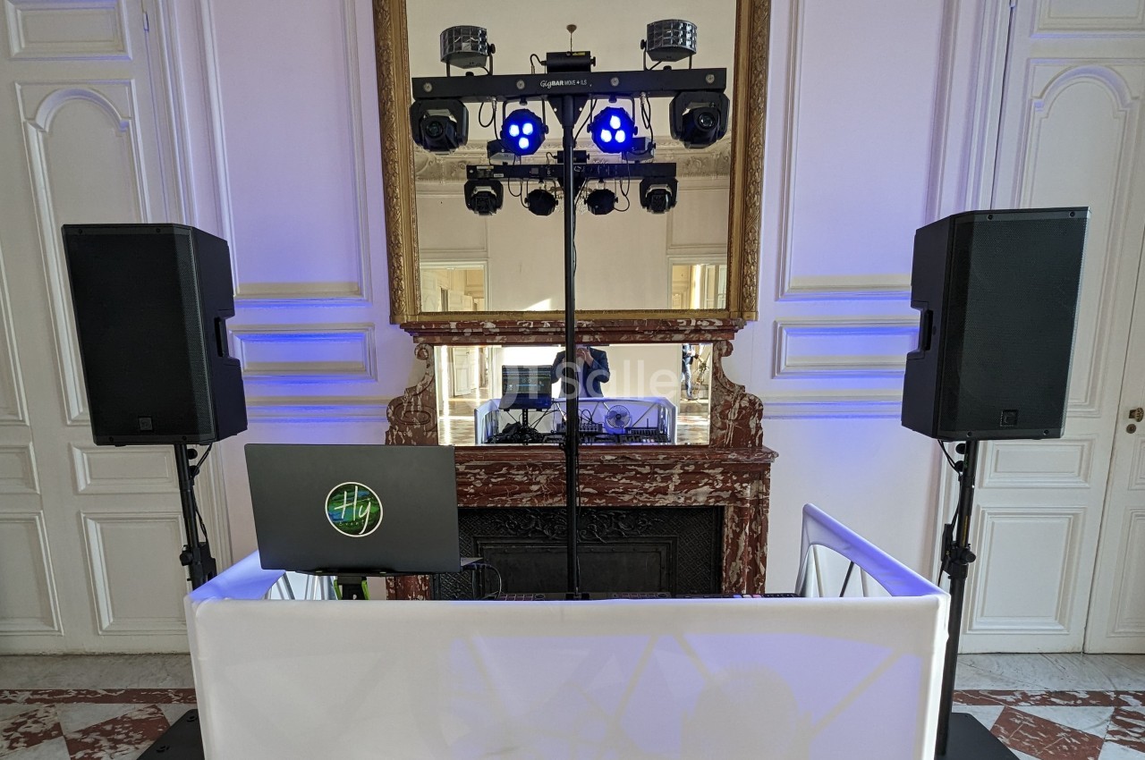 Installation de matériel de sonorisation et d'éclairage devant une cheminée dans une salle élégante.