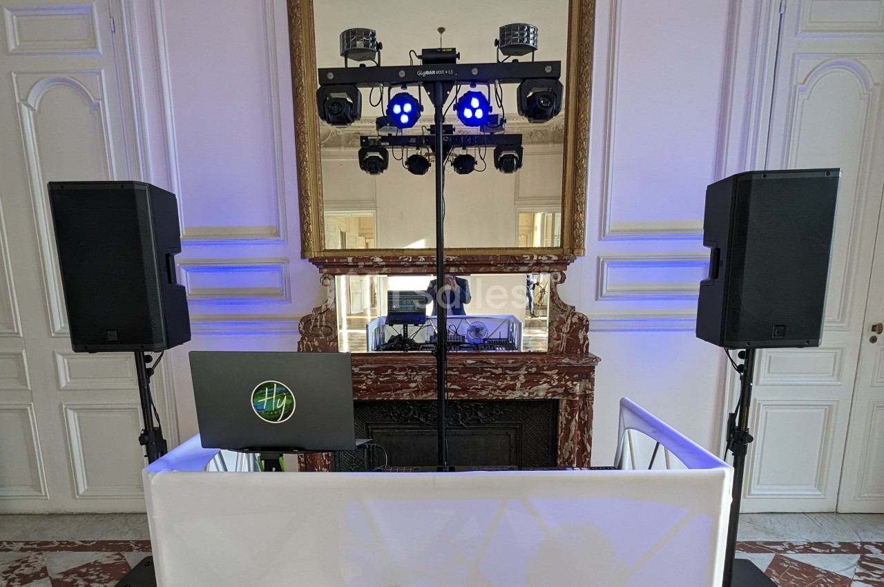 Installation de matériel de sonorisation et éclairage devant une cheminée dans une salle au style classique.