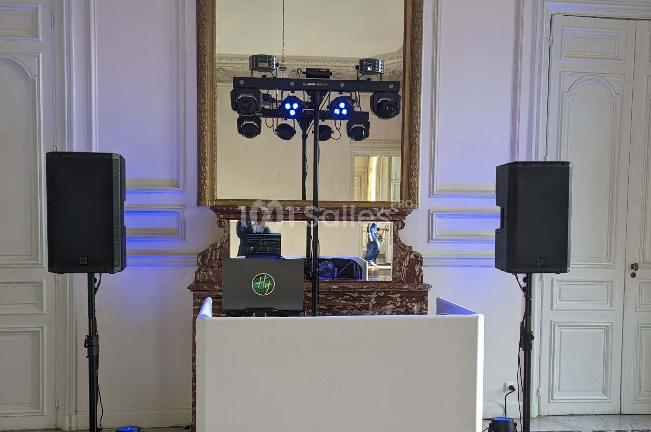 Installation de matériel de sonorisation et d'éclairage dans une salle avec miroir et murs blancs.