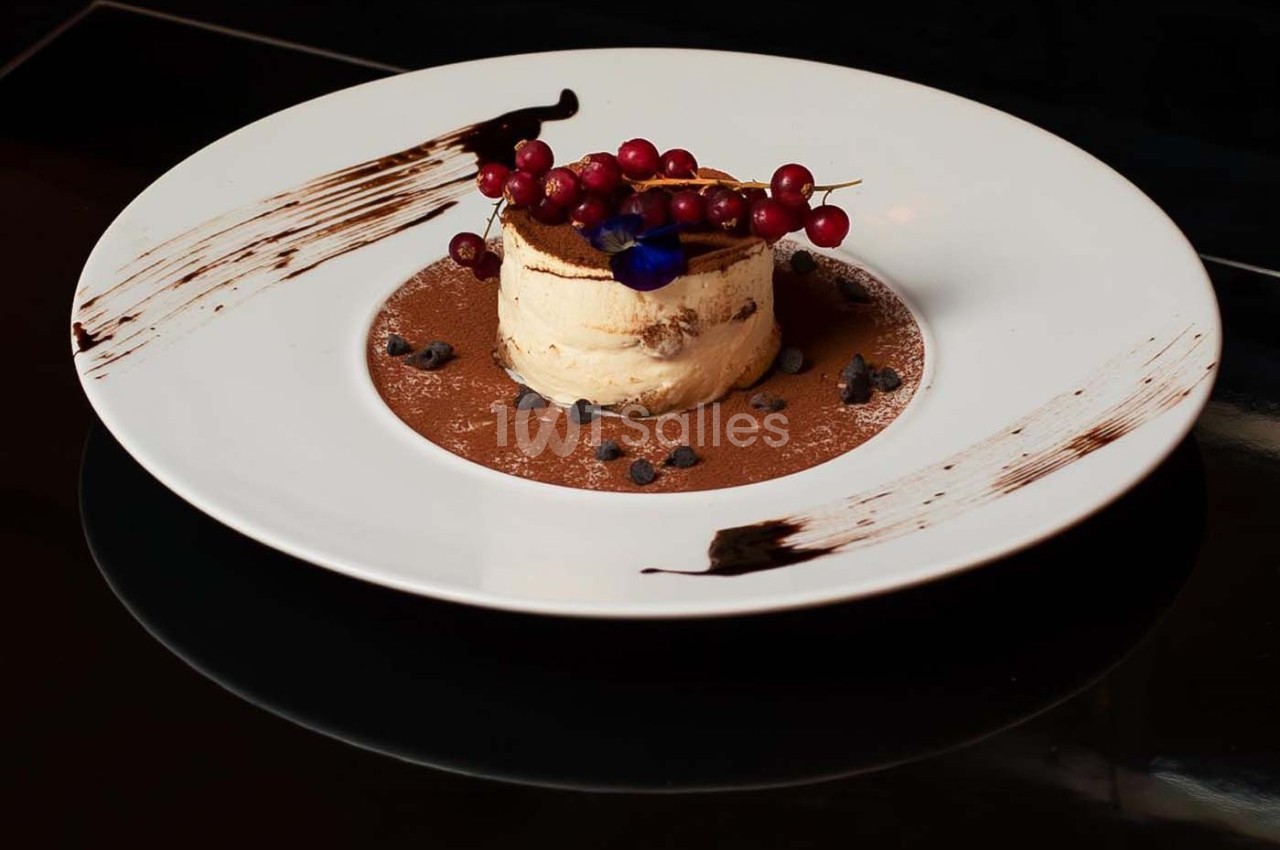 Dessert dressé sur une assiette blanche, composé de mousse, de fruits rouges et de décorations en chocolat.