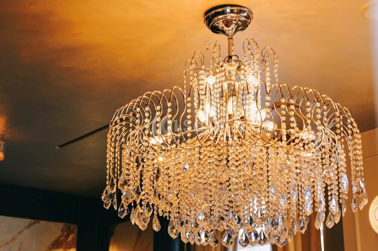 Lustre en cristal suspendu, illuminé, avec des détails étincelants dans un intérieur au plafond doré.
