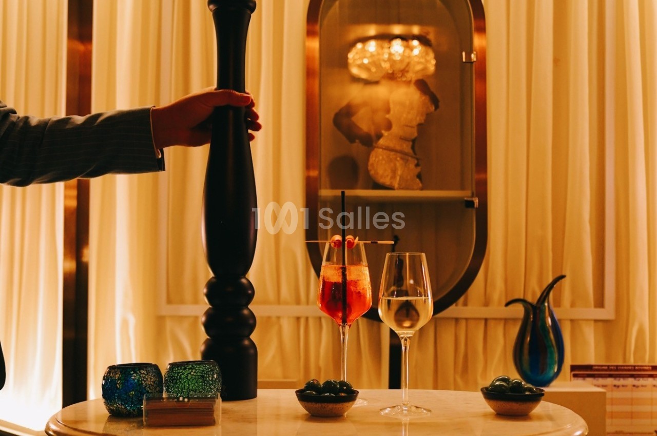 Deux verres de boissons sur une table élégante, entourés de bougies, olives et décorations dans un intérieur chaleureux.