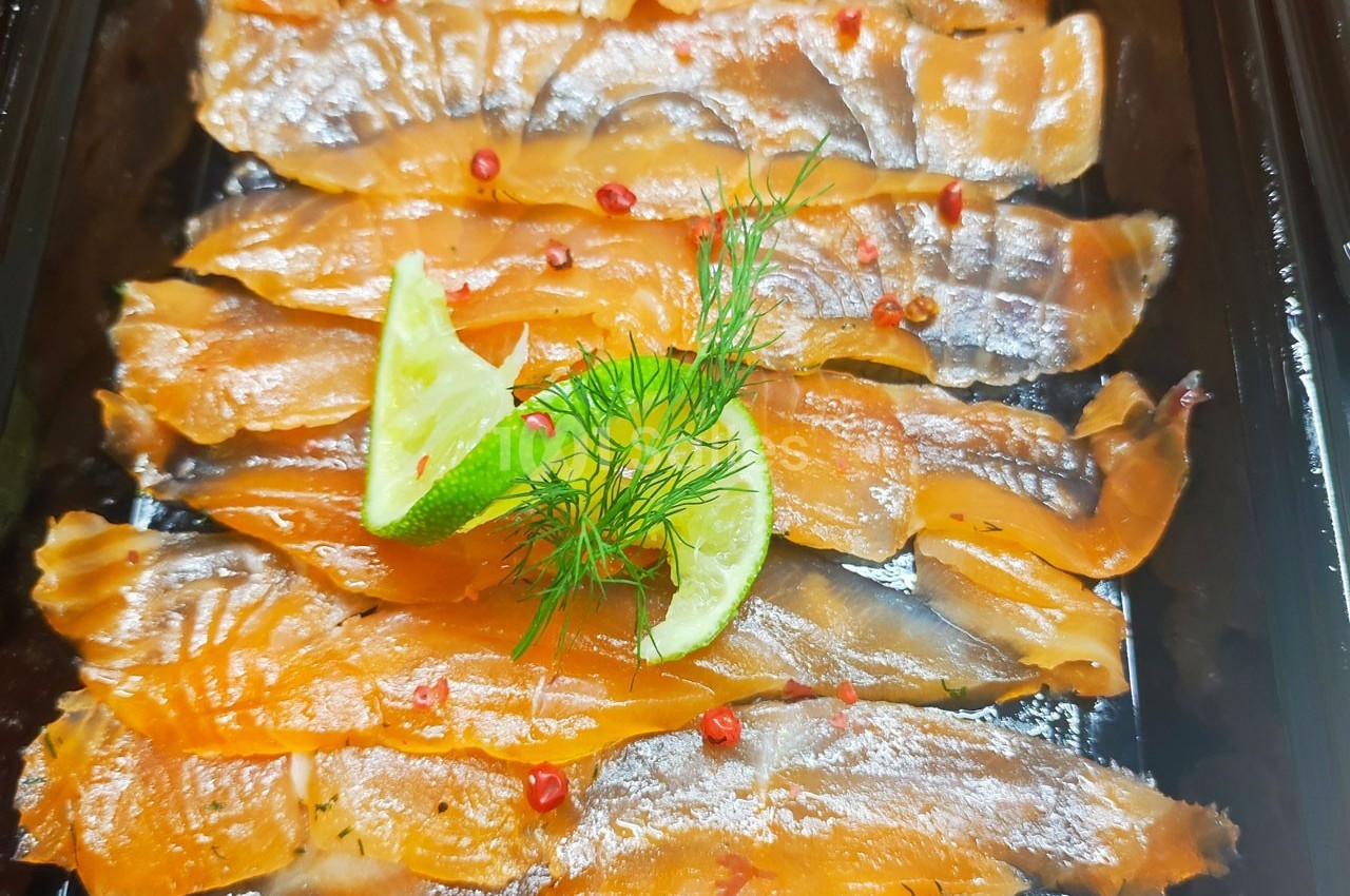 Tranches de saumon fumé garnies de rondelles de citron vert, brins d'aneth et baies roses.
