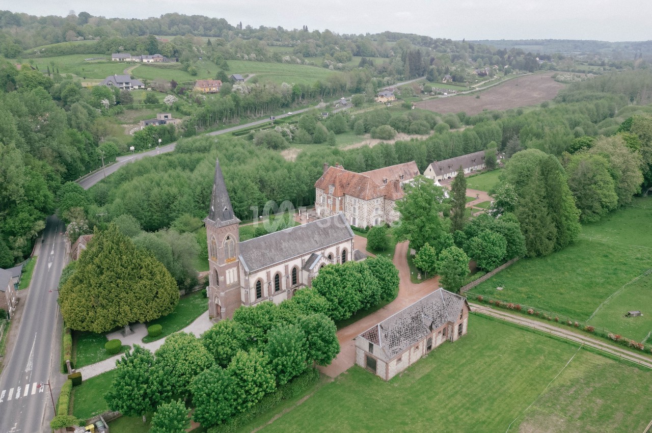 Vue aérienne d'une église entourée de bâtiments anciens, de routes et de paysages verdoyants.