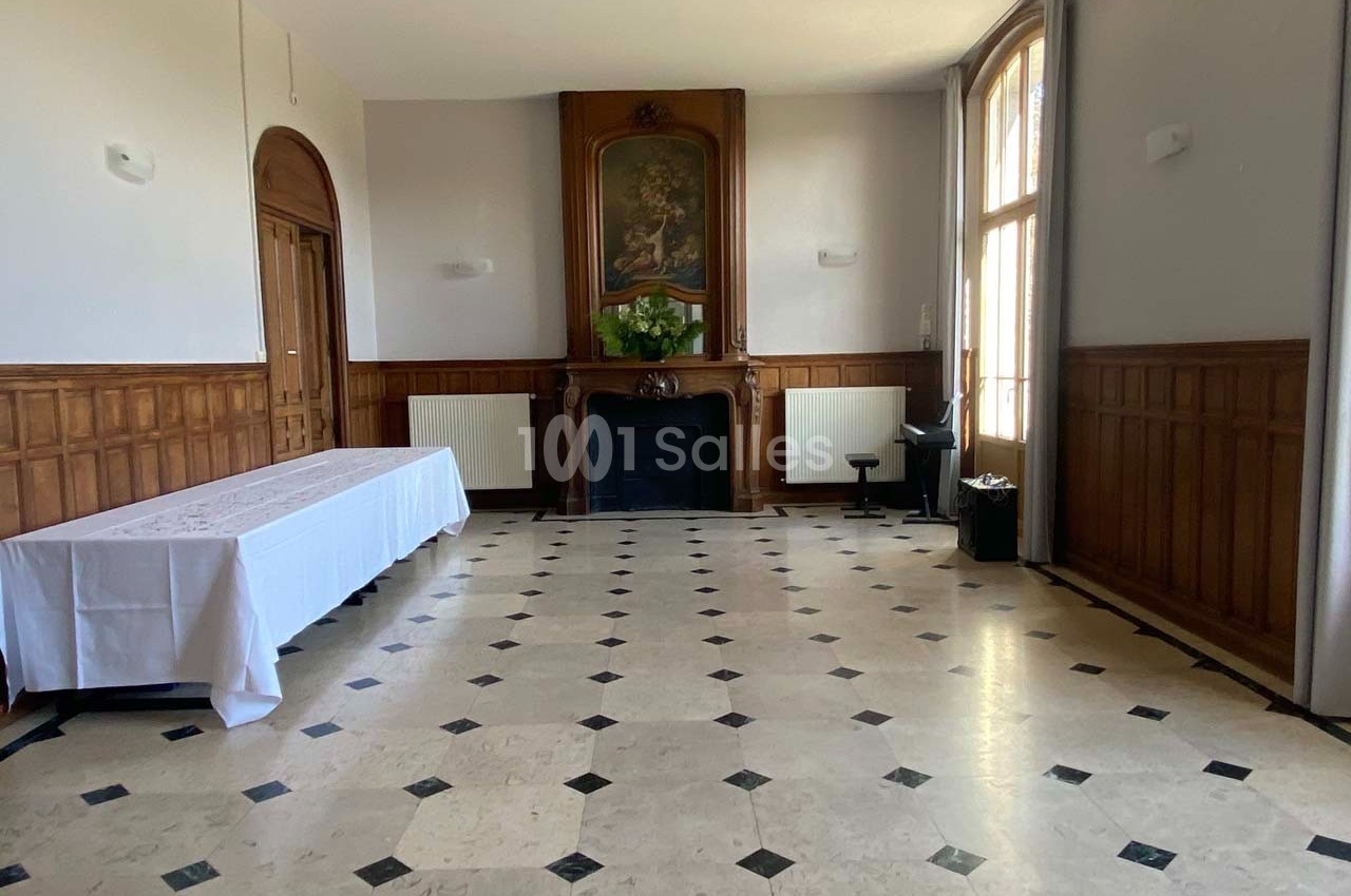 Salle lumineuse avec sol en marbre, murs en bois, cheminée décorative et grande fenêtre laissant entrer la lumière naturelle.