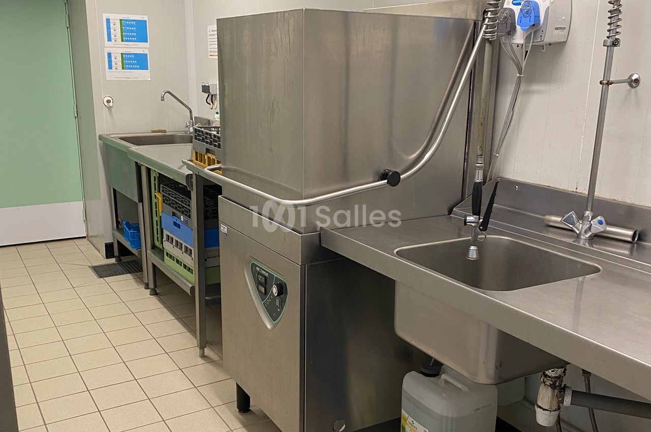 Cuisine professionnelle avec un lave-vaisselle industriel, un évier en inox et des plans de travail en acier.