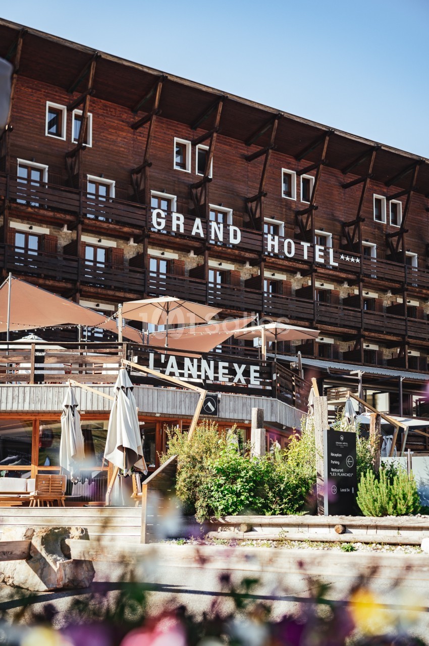 Façade en bois d'un hôtel avec balcons, terrasses ombragées et enseignes ’Grand Hôtel’ et ’L'Annexe’.