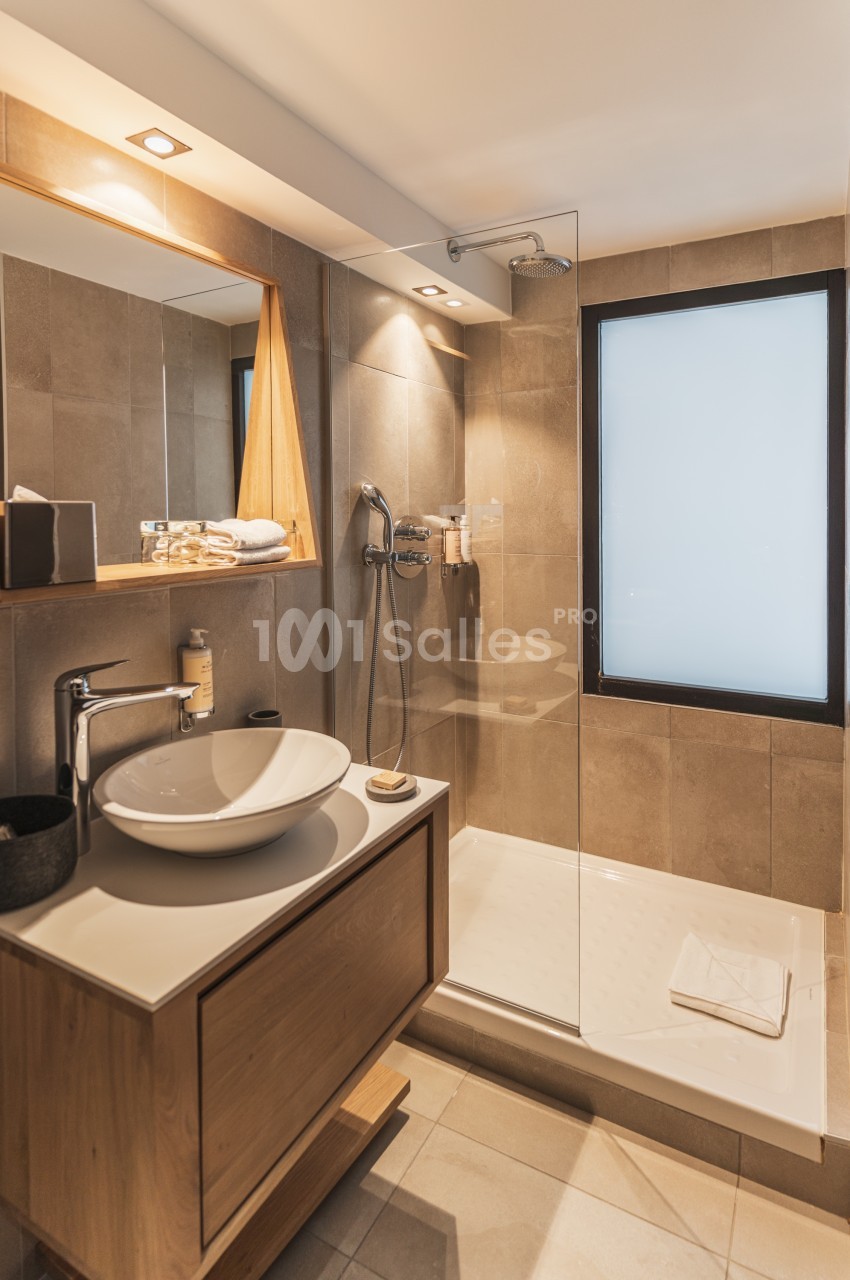 Salle de bain moderne avec douche à l'italienne, vasque sur meuble en bois et éclairage intégré.