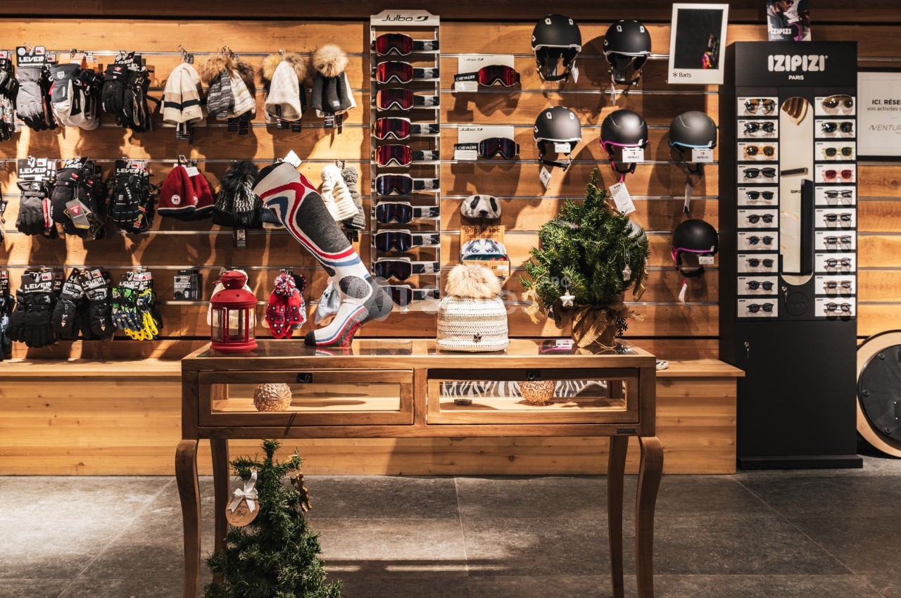 Mur d'accessoires de sports d'hiver avec gants, casques et lunettes, table décorative au premier plan.