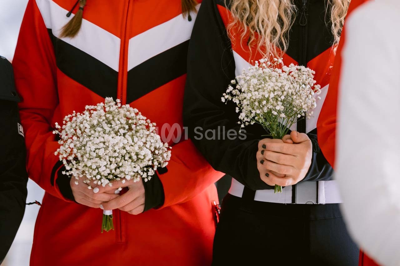 Deux personnes en tenue rouge et noire tiennent des bouquets de gypsophiles blanches dans leurs mains.