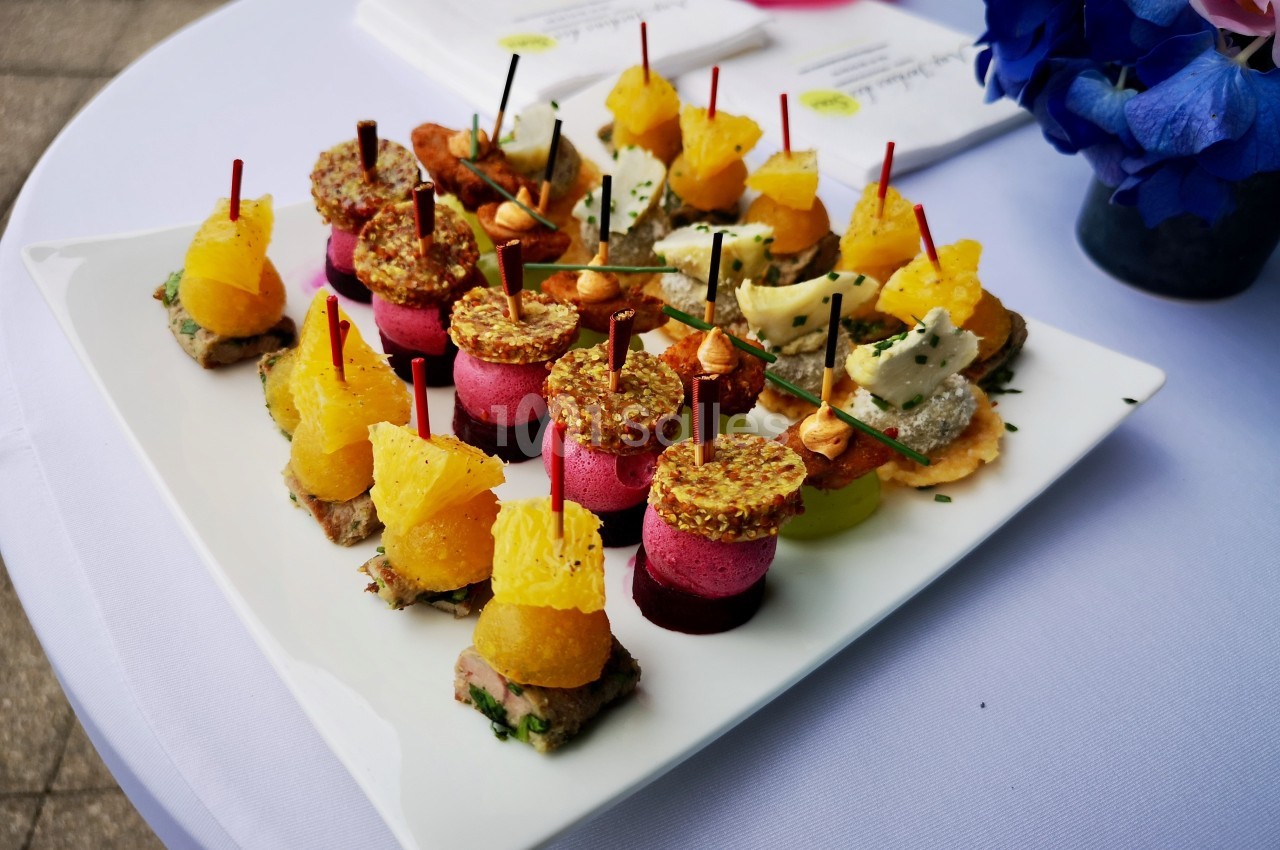 Assortiment de bouchées colorées sur un plateau blanc, disposées sur une table avec une nappe blanche.