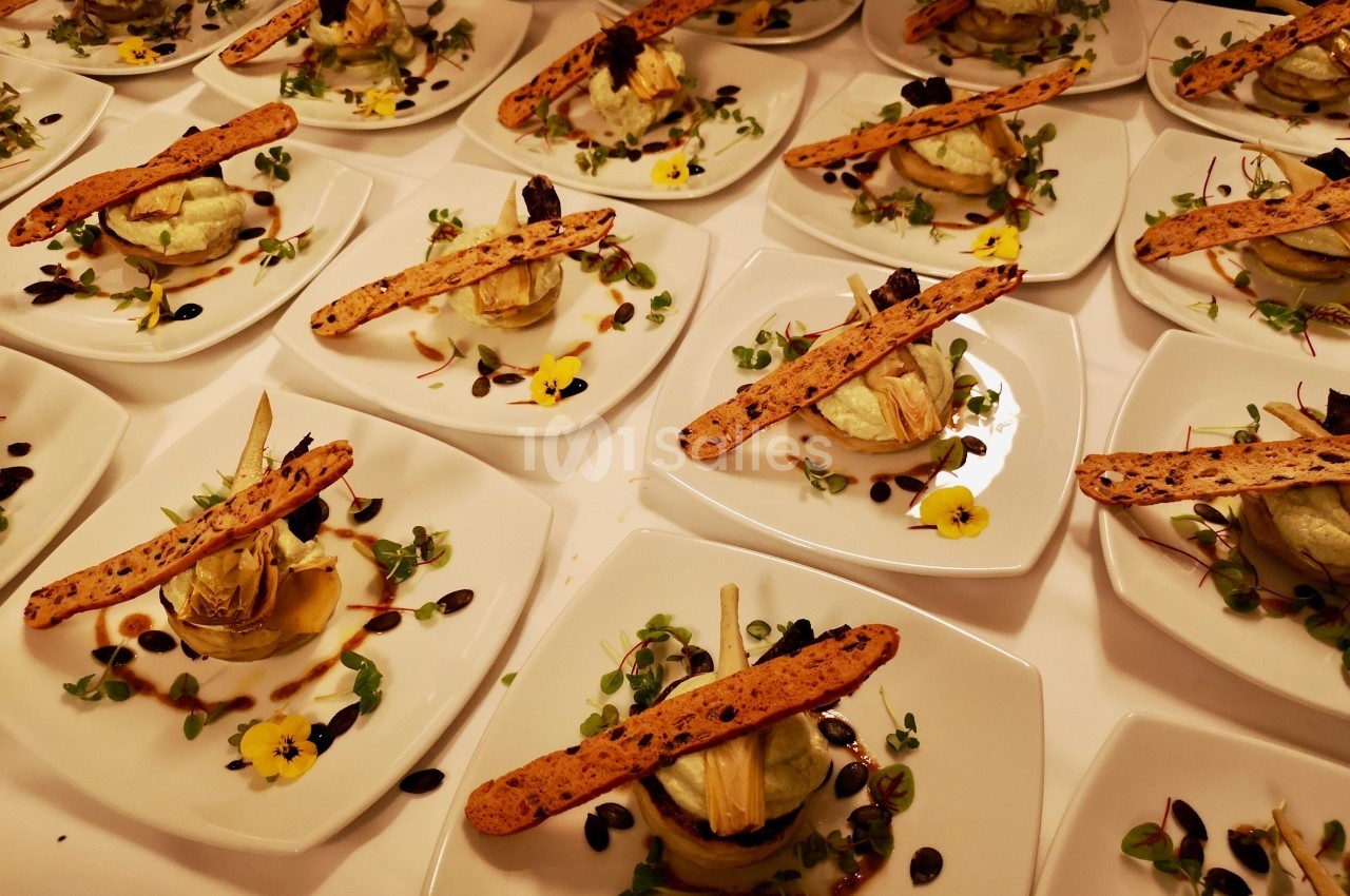 Assiettes dressées avec des entrées composées de légumes, herbes, fleurs comestibles et fines tranches de pain.