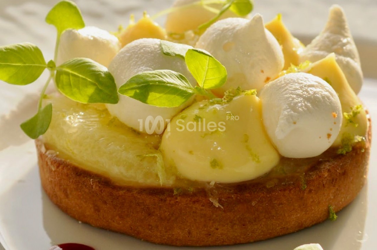 Tartelette garnie de crème citronnée, meringues légères, zestes de citron vert et décorée de feuilles fraîches.