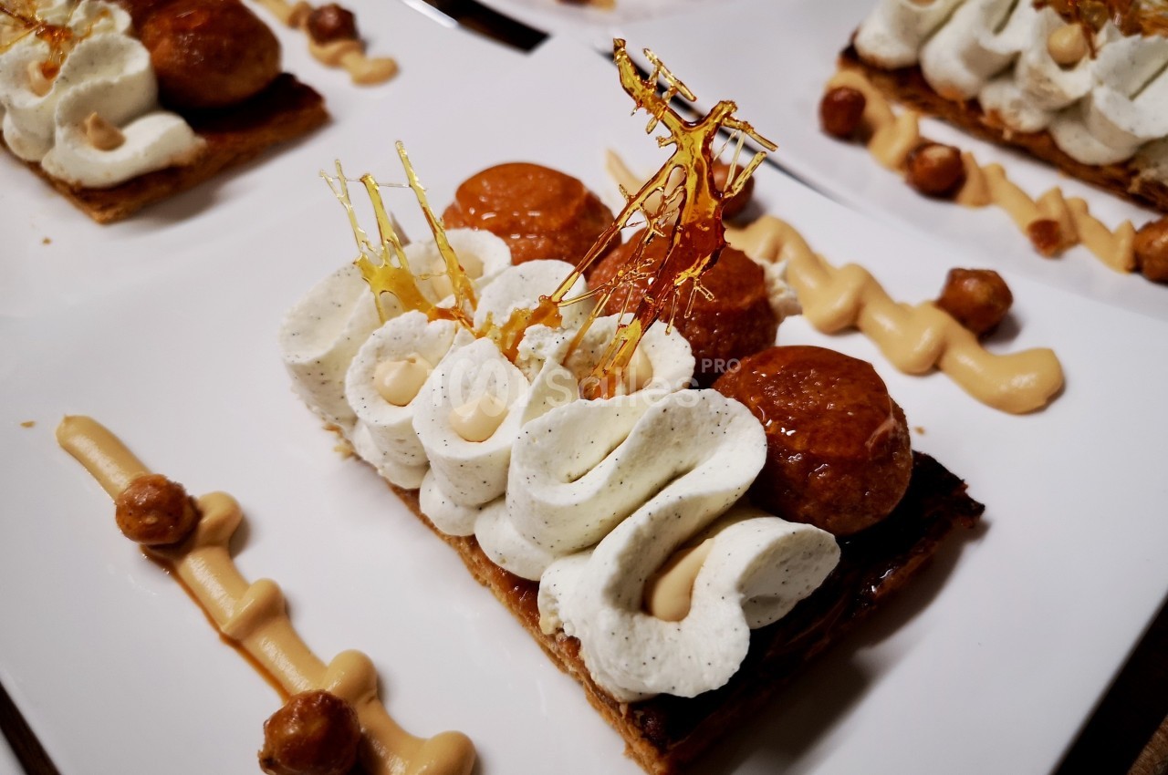 Dessert composé de pâte feuilletée, crème chantilly, choux caramélisés et décorations en caramel.
