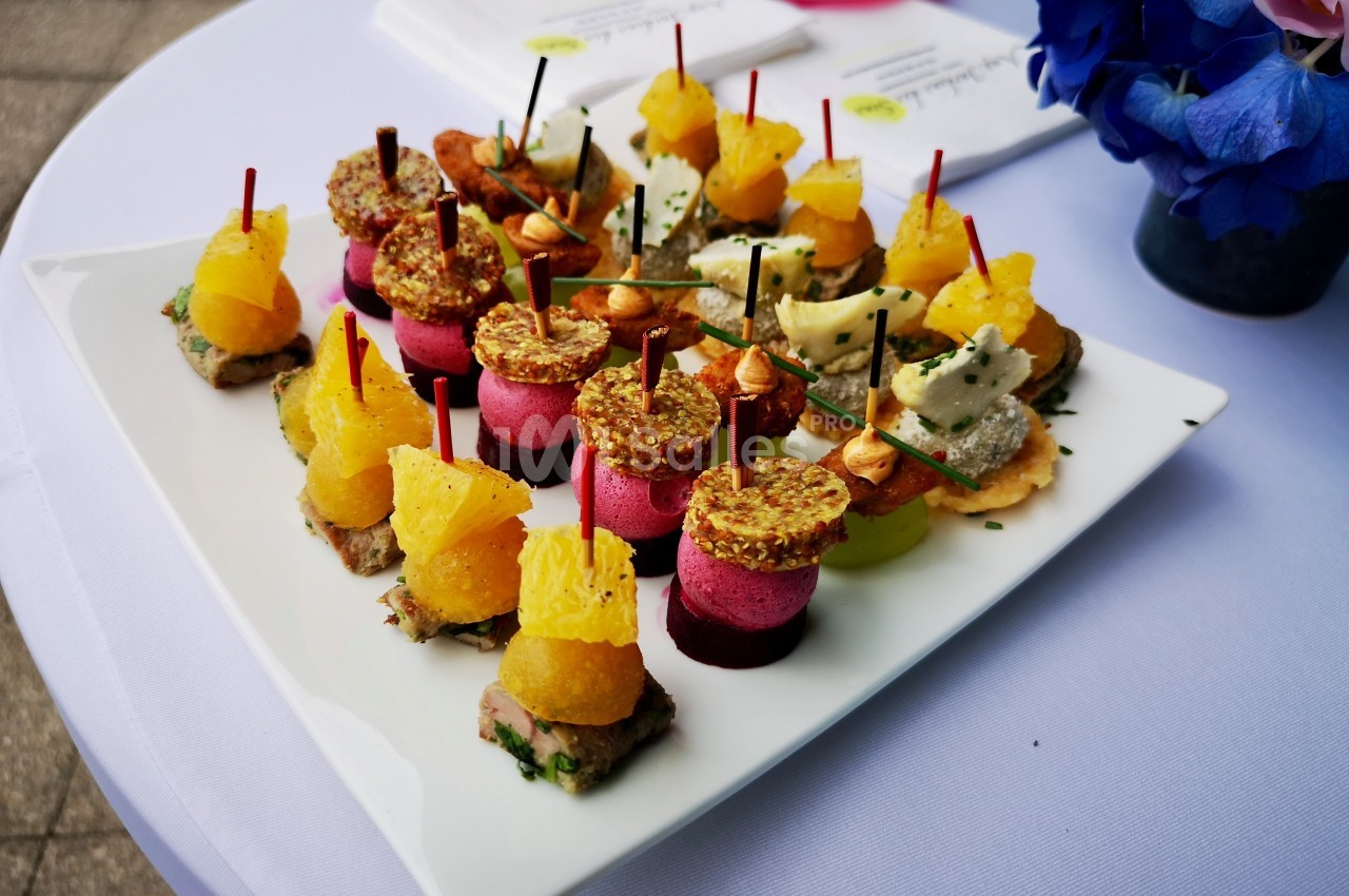 Assortiment de bouchées colorées sur un plateau blanc, disposées sur une table avec une nappe blanche.